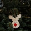 A wooden reindeer ornament hangs from a christmas tree.