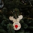 A wooden reindeer ornament hangs from a christmas tree.