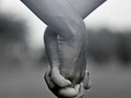A black and white photo of two people holding hands.