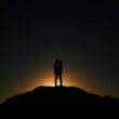 A silhouette of a couple standing on top of a hill at sunset.