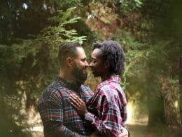 A couple embraces in the woods during their engagement session.
