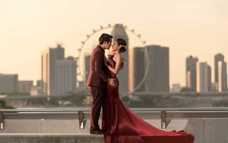 A bride and groom kissing in front of a city skyline.