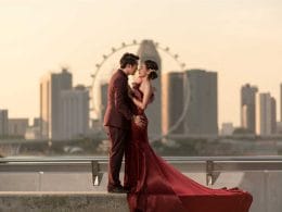 A bride and groom kissing in front of a city skyline.