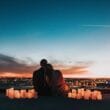 A couple sitting on top of a building with candles in front of them.