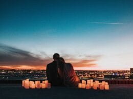 A couple sitting on top of a building with candles in front of them.