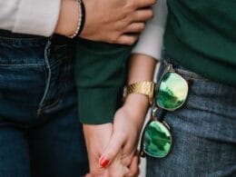 A couple holding hands while wearing green sunglasses.