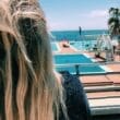 A woman with long blonde hair looking out over the pool.