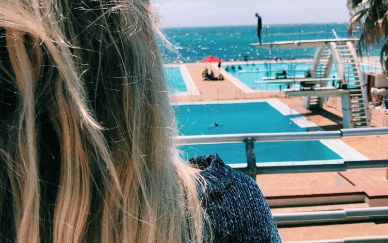 A woman with long blonde hair looking out over the pool.