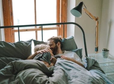 A man and woman hugging in bed.