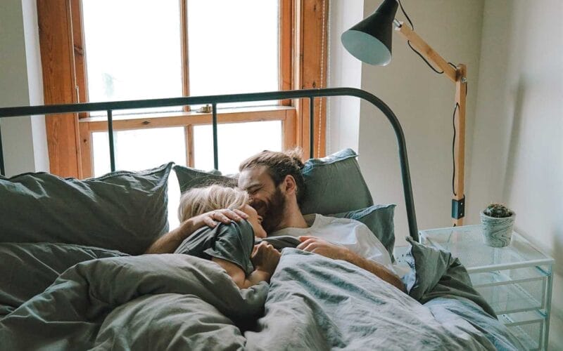 A man and woman hugging in bed.